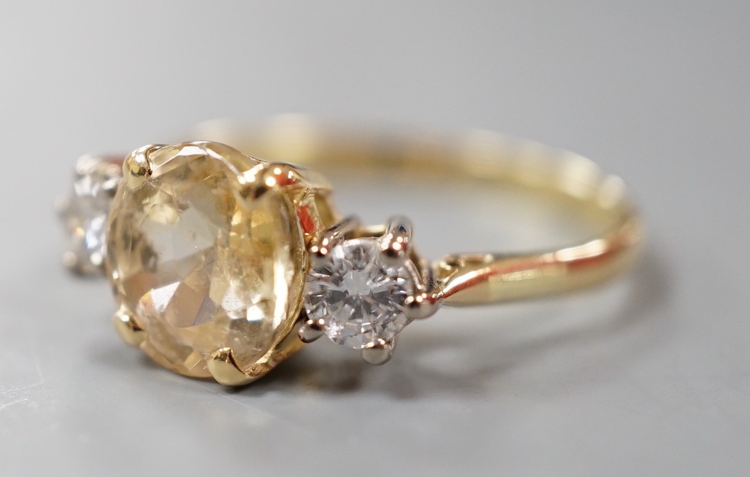 A yellow metal, singe stone oval cut yellow sapphire and two stone round cut diamond set ring, size N/O, gross weight 2.9 grams.